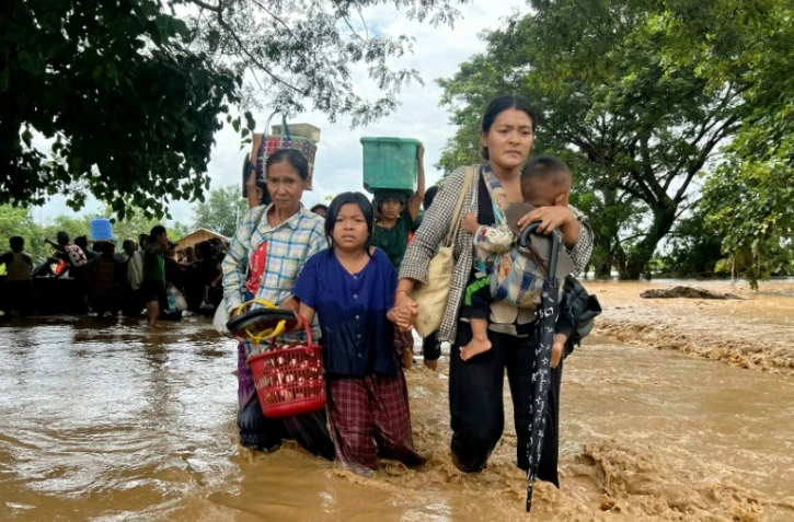Des habitants marchent dans les eaux à Pyinmana, dans la région de Naypyidaw en Birmanie, le 13 septembre 2024, à la suite de fortes pluies consécutives au typhon Yagi