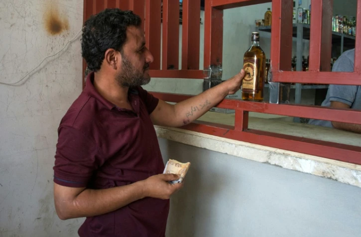 Un Irakien achète une bouteille de whisky dans une échoppe, le 10 mai 2017 à Mossoul