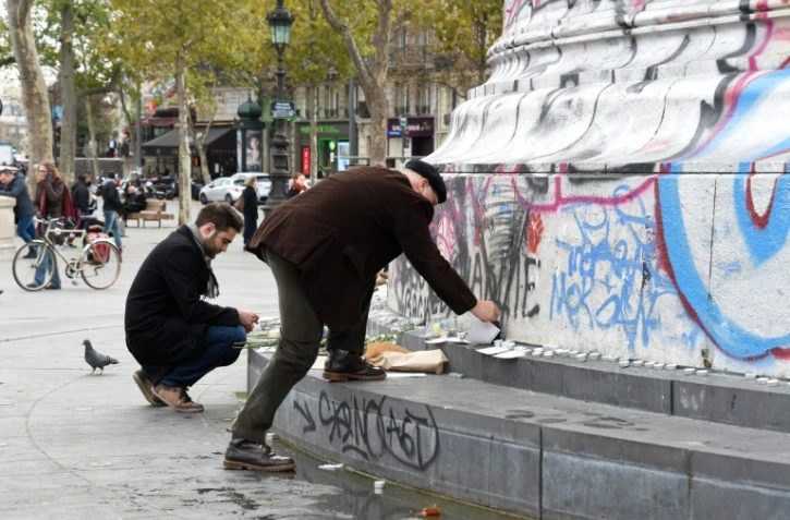 Des personnes posent des fleurs et des bougies face au monument de la Place de la République, le 14 novembre 2015 à Paris 