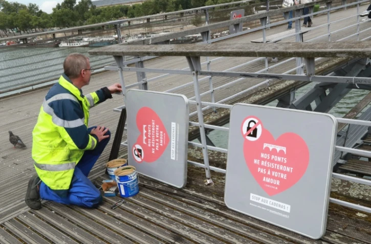 Installation d'affiches pour dissuader les touristes d'accrocher des "cadenas d'amour", le 4 août 2016 sur le Pont Neuf à Paris