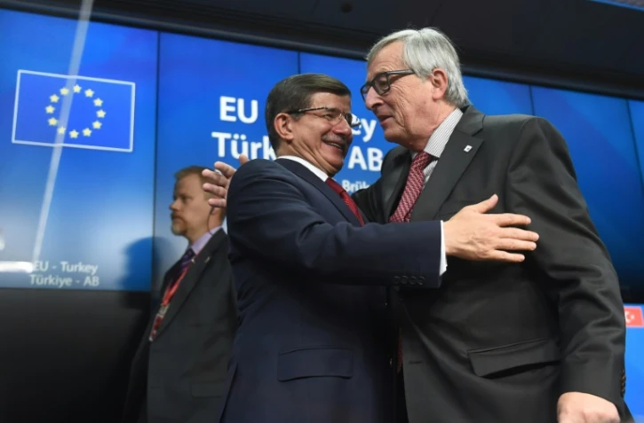 Le Premier ministre turque Ahmet Davutoglu (g), salue le président de la Commission européenne Jean-Claude Juncker, lors d'une conférence de presse à la fin d'un sommet entre l'Union européenne et la Turquie, à Bruxelles, le 29 novembre 2015