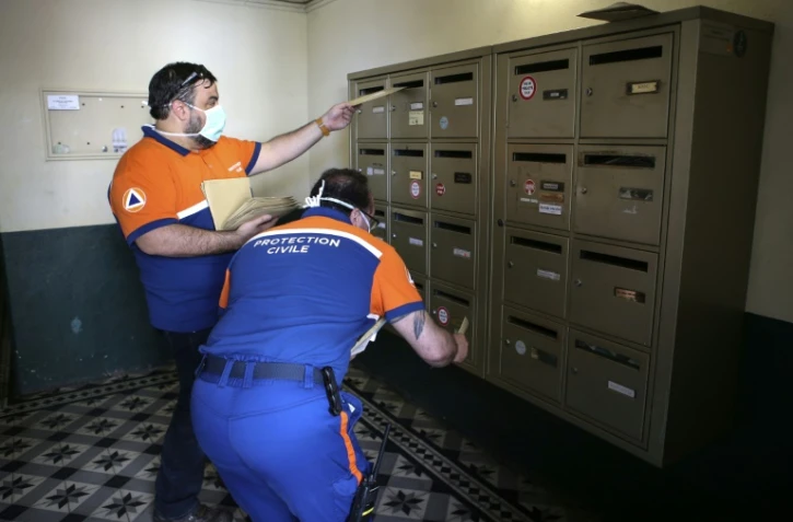 Des membres de la Protection civile distribuent des masques dans les boites Ă lettres d'habitants d'Ajaccio, en Corse, le 7 mai 2020