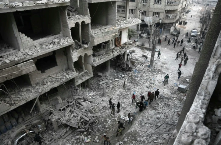 Des civils face aux dégâts causés par des raids aériens de l'aviation syrienne et de son allié russe à Hamouria, dans la Ghouta orientale, enclave rebelle à l'est de Damas, le 6 janvier 2018