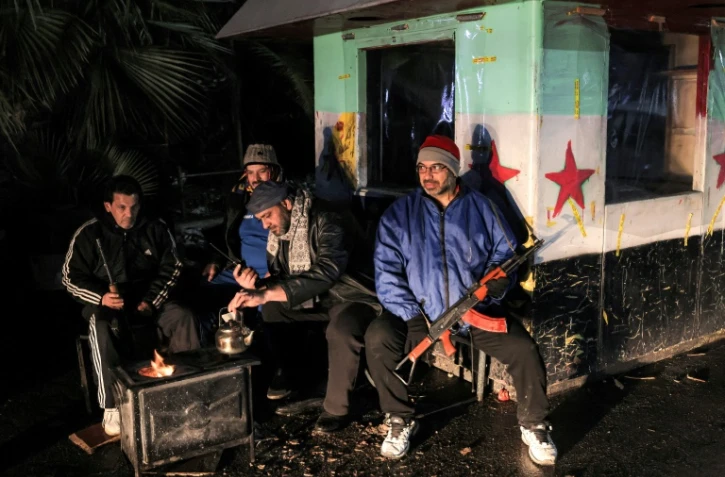 Des habitants de Damas sur un poste de contrôle du quartier de Chaghour, le 29 décembre 2024