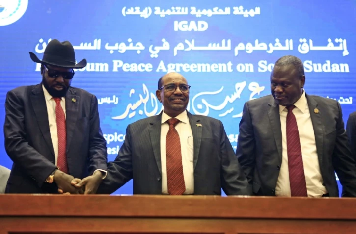 Le président soudanais Omar el-Béchir (C) tient les mains du président sud-soudanais Salva Kiir (G) et du chef rebelle Riek Machar (D) après la signature à Khartoum d'un accord de cessez-le-feu, le 27 juin 2018