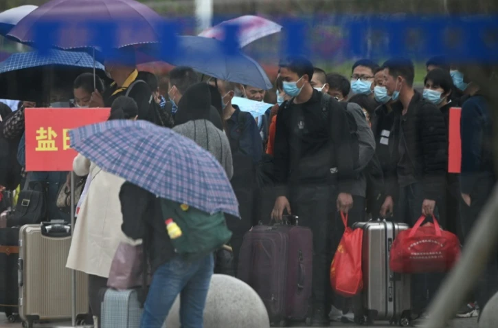 Des personnes portant un masque de protection font la queue pour acheter un billet de train Ă la gare de Macheng, le 25 mars 2020 dans la province chinoise du Hubei
