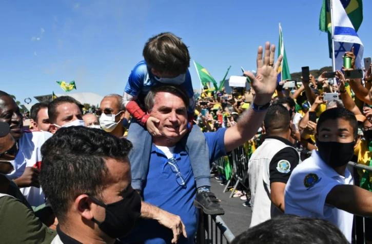 Le président brésilien Jair Bolsonaro porte le fils d'un de ses partisans lors d'un rassemblement à Brasilia le 31 mai 2020