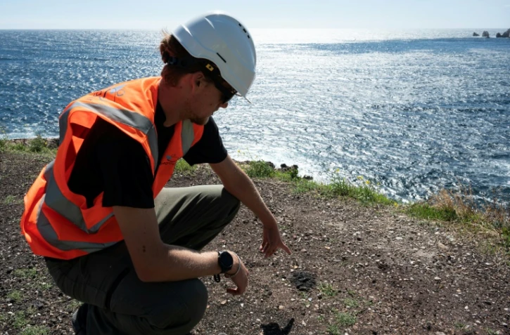 Un agent montre des dépôts de scories lors d'une visite de presse sur l'avancement des travaux de dépollution aux "Goudes", un quartier et port du 8e arrondissement de Marseille, porte sud de la ville et du Parc National des Calanques, le 11 septembre 2025