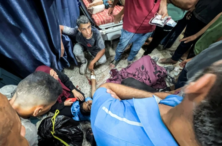 Des Palestiniens entourent l'une des personnes blessées en attendant de l'aide humanitaire près du point de passage de Zikim, dans le nord de la bande de Gaza, le 30 juillet 2025