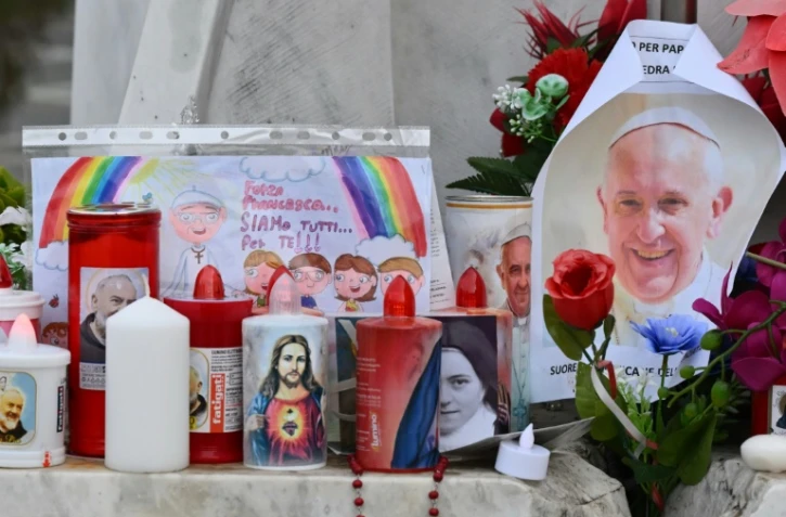 Des chandelles, des fleurs et un portrait du pape François déposés devant l'hôpital où se trouve le souverain pontife le 24 février 2025 à Rome