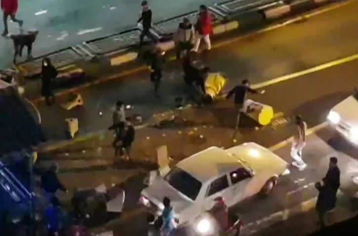 Image extraite d'une vidéo fournie par l'agence iranienne Mehr News montrant un groupe d'hommes tapant dans des plots de circulation dans une rue de Téhéran le 30 décembre 2017