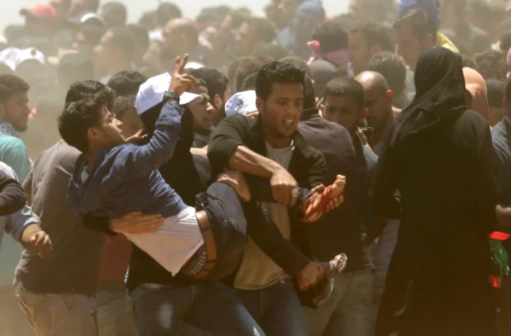 Des palestiniens transportent un manifestant blessé lors de heurts avec des soldats israéliens à Gaza le 14 mai 2018