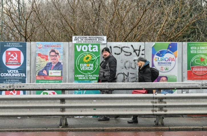 Des passants marchent devant des panneaux électoraux le 19 janvier 2020 à Bologne, avant les élections régionales en Emilie-Romagne (Italie)