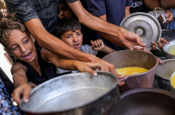 Des enfants palestiniens font la queue pour recevoir des repas d'une  organisation caritative locale à Gaza-ville, le 14 juillet 2025