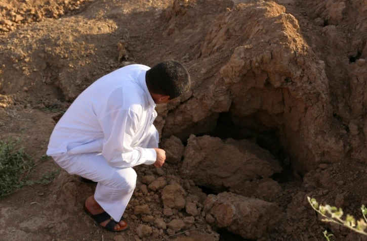 Un Irakien examine le site où sont enterrés des jihadistes de l'EI à Dhoulouïya, à 90 km au nord de Bagdad, le 10 octobre 2017