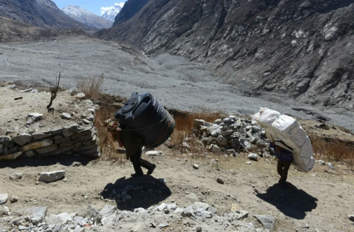 Des porteurs avec différents matériaux sur le dos qui doivent servir à reconstruire le village de  Langdang au Népal, le 6 avril 2016