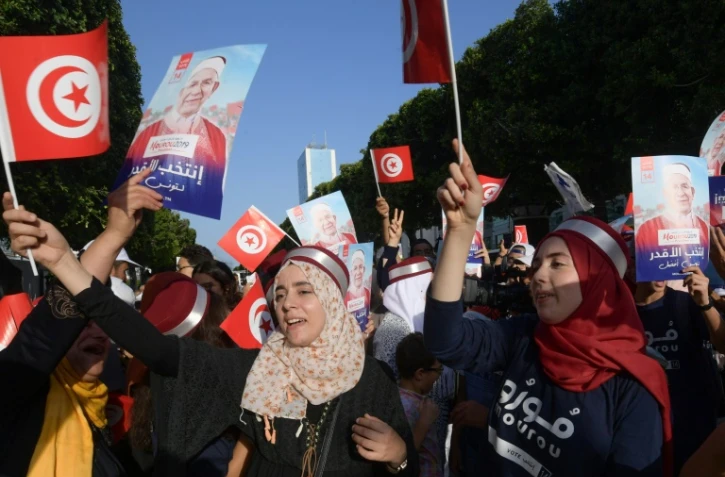 Des partisans du candidat à l'élection présidentielle tunisienne du mouvement islamiste Ennahdha Abdelfattah Mourou (portrait) font campagne le long de l'avenue Habib Bourguiba, dans le centre de Tunis, le 13 septembre 2019