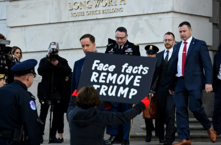 Une manifestante en faveur de la destitution de Donald Trump tient une pancarte à la sortie du  lieutenant-colonel Alexander Vindman, témoin dans l'enquête visant le président américain, le 19 novembre 2019