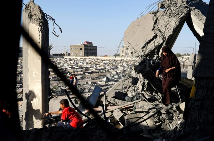 Une femme et des enfants palestiniens dans les décombres d'une maison touchée par des bombardements israéliens nocturnes à Rafah, dans le sud de la bande de Gaza, le 20 avril 2024