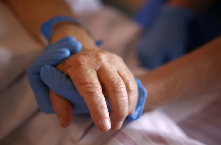Un personnel soignant tient la main d'un patient en soins palliatifs, à l'hôpital Eugénie d'Ajaccio, le 23 avril 2020