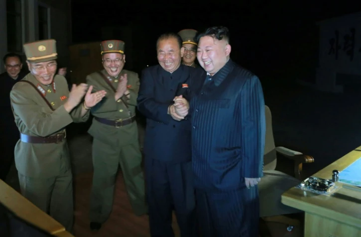 Une photo diffusée le 28 juillet 2017 par l'agence officielle nord-coréenne KCNA montrant le leader nord-coréen Kim Jong-Un (d) célébrant un lancement de missile balistique dans un endroit non divulgué en Corée du Nord