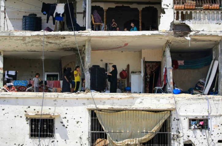 Des familles palestiniennes retournent dans leurs maisons gravement endommagées dans un immeuble touché lors d'un précédent bombardement israélien, dans la ville de Khan Younés, dans le sud de la bande de Gaza, le 30 juin 2024