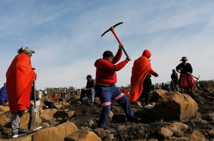 Une femme munie d'une pioche pour chercher ce qu'elle pense être des diamants, dans le village sud-africain de KwaHlathi le 15 juin 2021