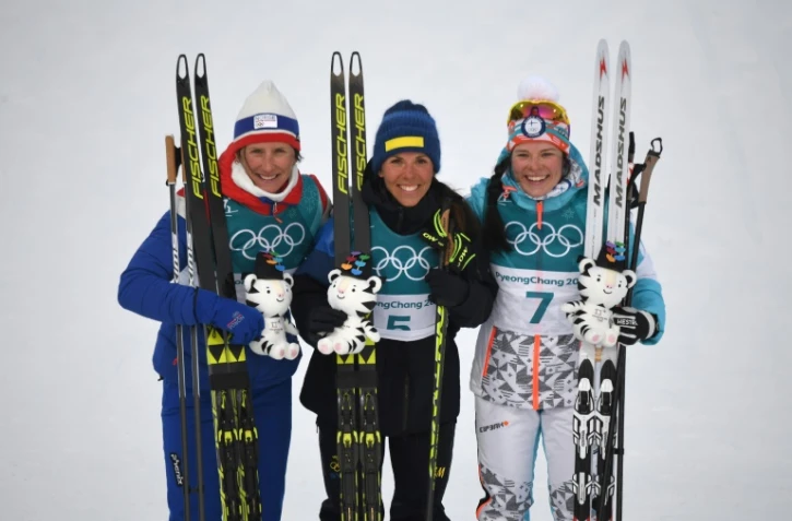 Charlotte Kalla (c) pose avec Marit Björgen (g) et Krista Parmakoski, après sa victoire en skiathlon aux JO (7,5 km classique), le 10 février 2018 à Pyeongchang