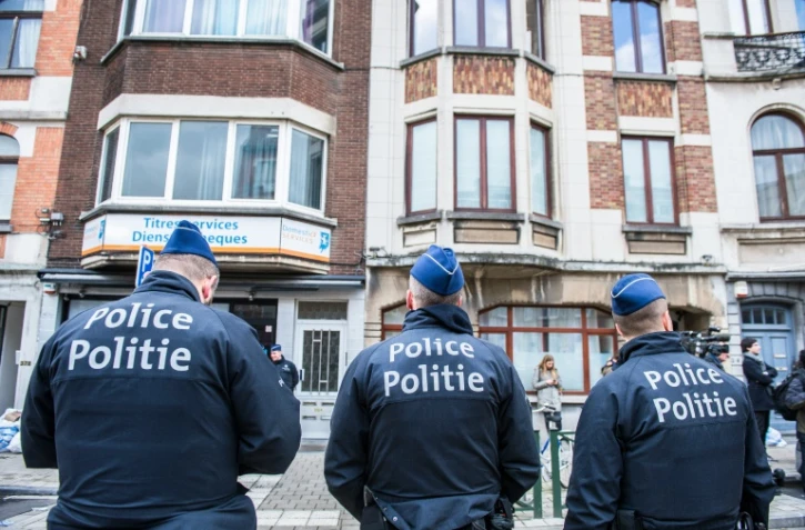 Trois officiers de police belges montent la garde dans la commune de Schaerbeek, dans la région de Bruxelles, le 25 mars 2016