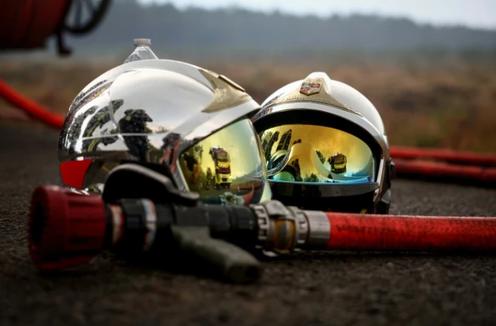 Deux casques de pompier et une lance à incendie gisent au sol alors qu'un incendie de forêt fait rage à Saint-Jean-d'Illac, à environ 30 km de Bordeaux, le 26 juillet 2026
