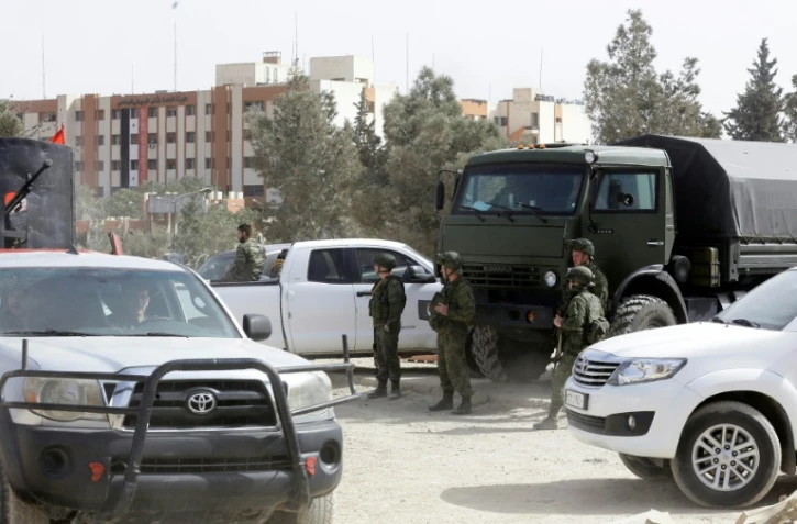 Des forces syriennes et des soldats russes, alliés de Damas, à l'entrée de la localité de Harasta, près de Damas, que des rebelles et des civils doivent quitter jeudi après un accord régime-insurgés.