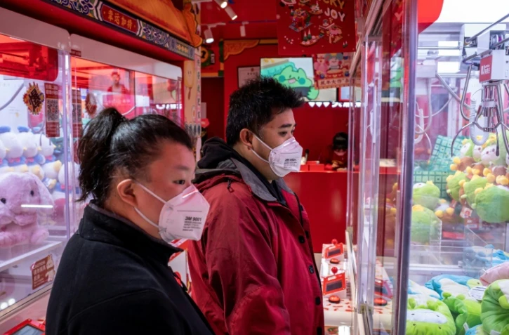 Des clients portent un masque de protection dans une boutique de Pékin, le 29 janvier 2020 en Chine