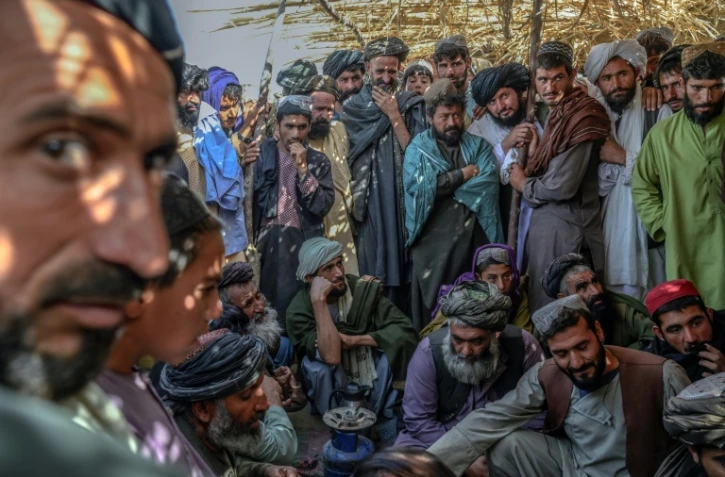 Des hommes rassemblés autour de sacs contenant de l'héroïne et du haschisch en vérifient la qualité, sur un marché à l'extérieur de Kandahar, en Afghanistan, le 24 septembre 2021