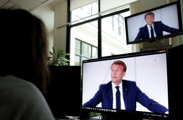 Une femme regarde une intervention télévisée du président français Emmanuel Macron le 14 juillet 2020 à Paris