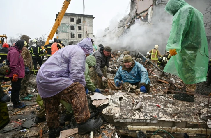 Des habitants nettoyent des débris après une frappe de missile russe sur des immeubles d'habitation dans la ville ukrainienne de Poltava, le 1er février 2025