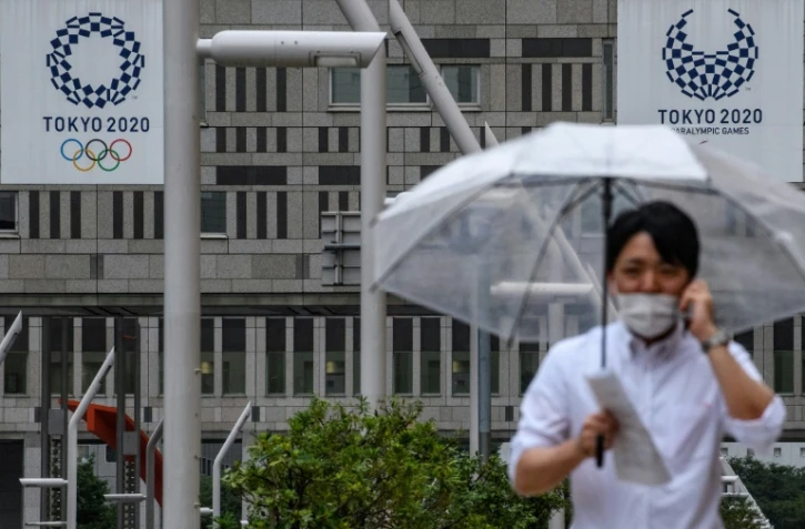 Un homme marche près du siège du gouvernement métropolitain de Tokyo où l'on aperçoit des affiches des JO-2020. Photo prise le 13 juillet 2020. 