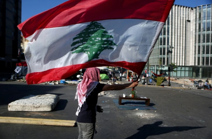 Un manifestant libanais agite le drapeau national à un barrage dans la capitale Beyrouth, le 30 octobre 2019