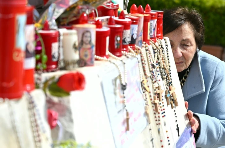 Une femme prie devant la statue de Jean-Paul II à l'extérieur de l'hôpital Gemelli où le pape François est hospitalisé à Rome, le 11 mars 2025. 