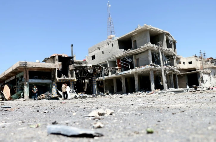 Des habitants inspectent des bâtiments endommagés par les raids nocturnes  du régime dans la ville de Nawa, dans la province de Deraa, le 18 juillet 2018