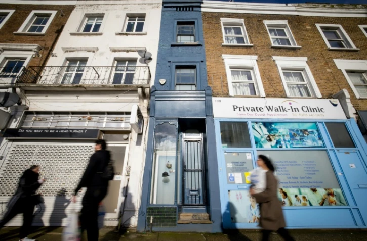 Des passants devant la façade bleue de la plus étroite maison de Londres (Royaume-Uni), le 5 février 2021