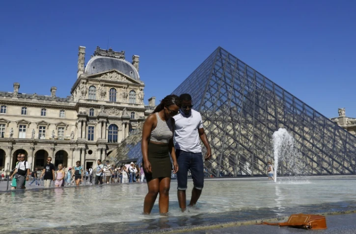 Les touristes qui ont bravé le soleil ont souvent fait trempette dans les fontaines parisiennes, comme ici devant la pyramide du Louvre