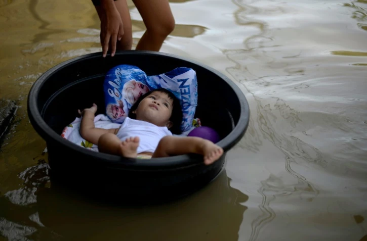 Un enfant allongé dans une bassine en plastique flotte au dessus de l'eau à Calampit Bucalan, à Manille, le 24 décembre 2015 