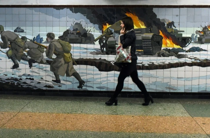 Une femme passe devant une mosaïque murale représentant une scène de bataille de la Deuxième guerre mondiale dans la ville russe de Rostov-sur-le-Don frontalière de l'Ukraine le 22 février 2022.