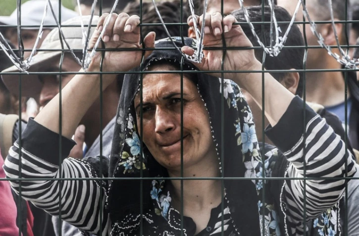 Une femme bloquée derrière la clôture de barbelés le 16 septembre 2015 à Horgos à la frontière entre la Hongrie et la Serbie 