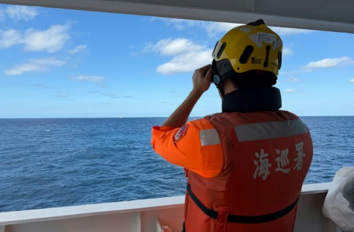 Cette photo fournie le 29 décembre 2025 par les garde-côtes taïwanais montre un agent observant un navire chinois, naviguant à 23 milles marins au nord-ouest de l'îlot Pengjia, au nord de Taïwan