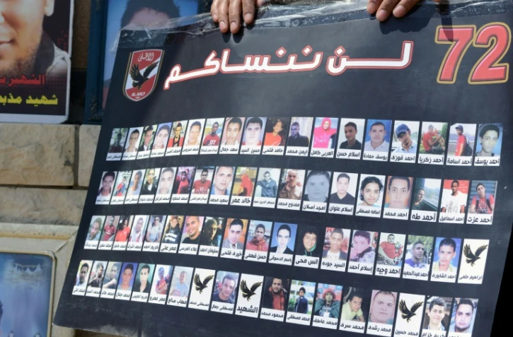 Une personne tient une affiche montrant les portraits des victimes des émeutes de Port Said en Egypte, le 9 juin 2015 au Caire