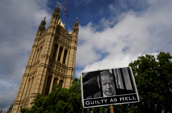 Une pancarte accuse le Premier ministre Boris Johnson d'être "aussi coupable que l'enfer" avant un vote de défiance, devant le Parlement à Londres le 6 juin 2022
