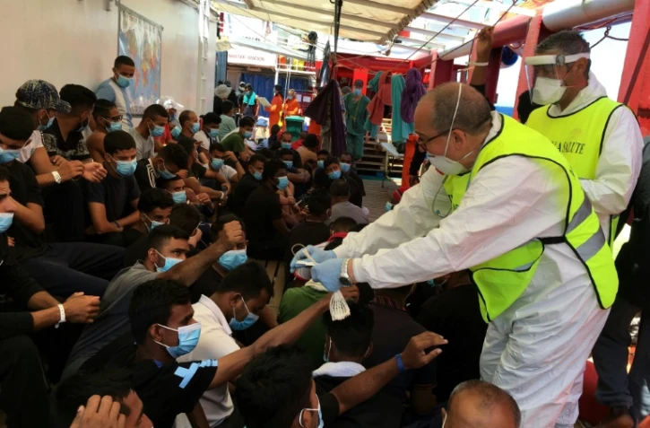 Un médecin italien distribue des bracelets numérotés à des migrans secourus sur le navire humanitaire Ocean Viking, le 5 juillet 2020 en Méditerranée
