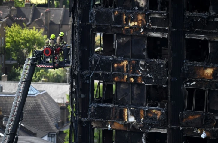 Des pompiers sur une grande échelle inspectent les décombres de la tour Grenfell à Londres le 16 juin 2017