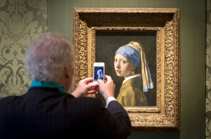 Un visiteur du musée Mauritshuis prend en photo "La Jeune Fille à la perle" de Vermeer, à La Haye, aux Pays bas, le 20 juin 2014